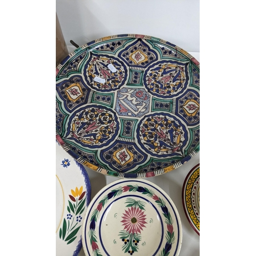 286 - A mixed lot to include a Moroccan ceramic charger, together with Quimper ware and stoneware bottles ... 