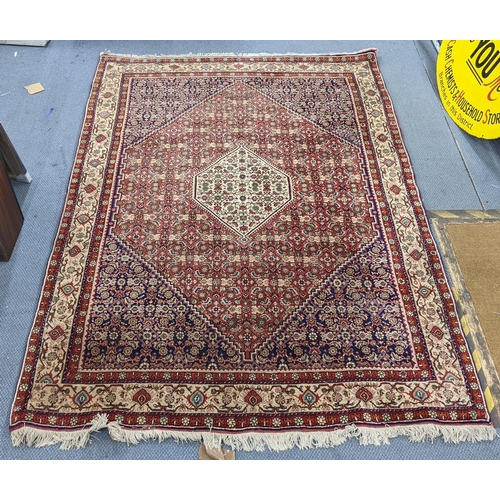 304 - A Persian Bijar hand woven rug having a red ground with a hexagon medallion and foliate borders, 225... 