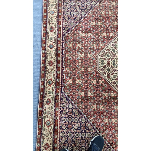 304 - A Persian Bijar hand woven rug having a red ground with a hexagon medallion and foliate borders, 225... 