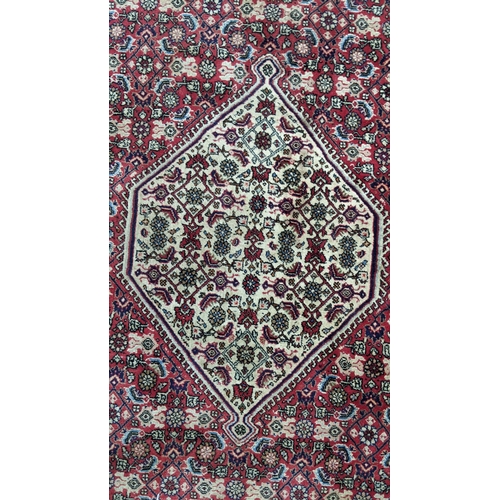 304 - A Persian Bijar hand woven rug having a red ground with a hexagon medallion and foliate borders, 225... 