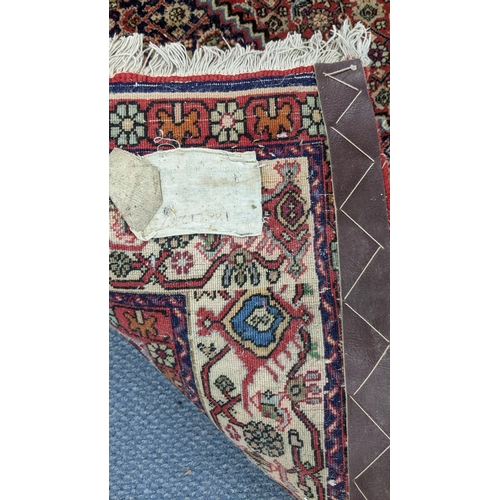 304 - A Persian Bijar hand woven rug having a red ground with a hexagon medallion and foliate borders, 225... 