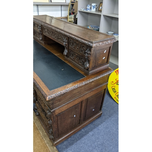 317 - A 19th century heavily carved oak twin pedestal desk having 14 drawers, half leather topped scriber ... 