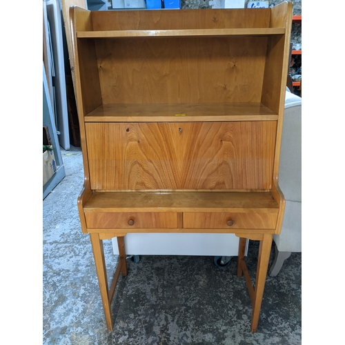 106 - A light wood bureau, open shelves above a fall flap revealing a fitted interior, over two drawers, o... 