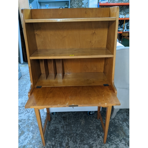 106 - A light wood bureau, open shelves above a fall flap revealing a fitted interior, over two drawers, o... 