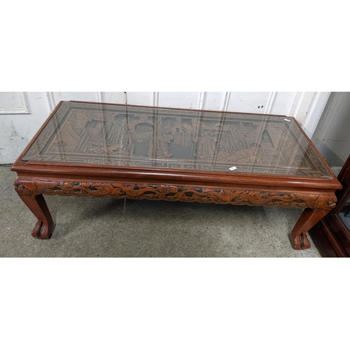 389 - A vintage Chinese coffee table having a carved top and border with a glass top, 37cm h x 102cm w
Loc... 