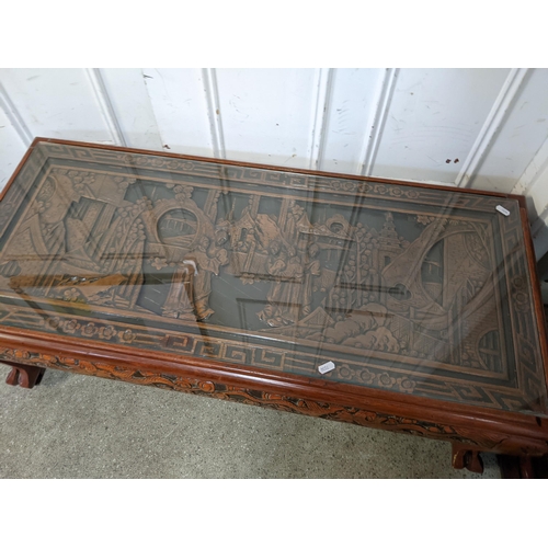 389 - A vintage Chinese coffee table having a carved top and border with a glass top, 37cm h x 102cm w
Loc... 