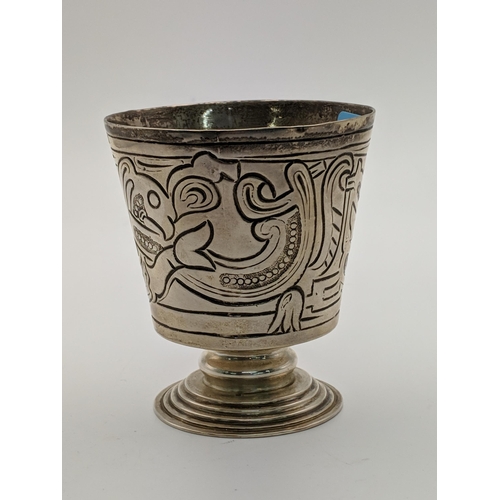 45 - A silver drinking vessel decorated with an abstract design raised on a circular stepped pedestal bas... 