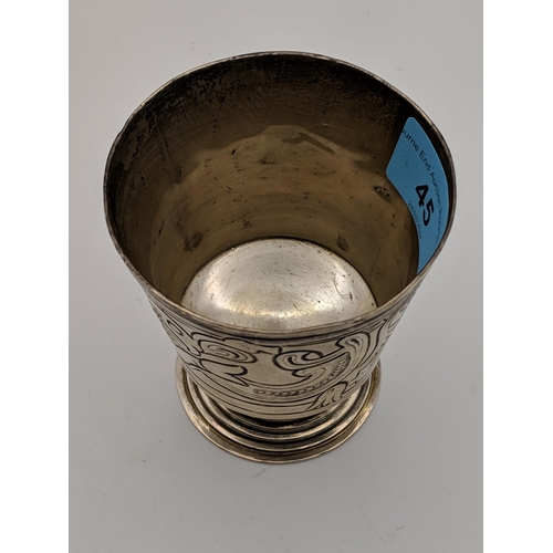 45 - A silver drinking vessel decorated with an abstract design raised on a circular stepped pedestal bas... 