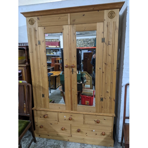 442 - A contemporary pine double wardrobe, stepped cornice above twin glazed doors, flanked by carved targ... 