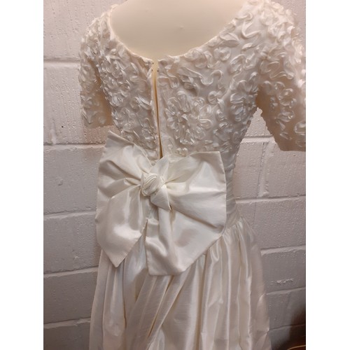 152 - A Donerica off white silk effect wedding dress having a zip fastening to the rear with large bow to ... 