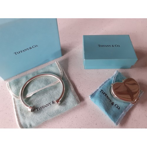 8 - Tiffany & Co-A silver horse shoe design bangle together with a Tiffany silver heart shaped pill box,... 
