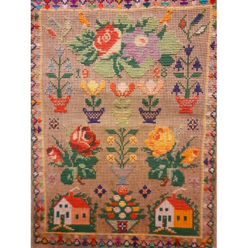 46 - A 1928 wool cross stitch sampler, unframed, with flowers in pots, roses and buildings, 36cm x 46cm. ... 