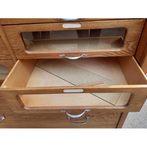 117 - A mid 20th Century hardwood veneered haberdashery cabinet having 20 glass fronted drawers A/F (one l... 