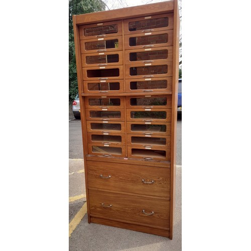 117 - A mid 20th Century hardwood veneered haberdashery cabinet having 20 glass fronted drawers A/F (one l... 