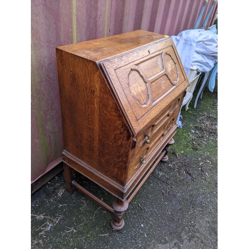 170 - An early 20th century oak bureau having a fall flap above two drawers, on bulbous supports, Location... 