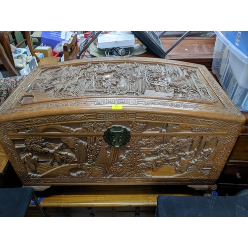 70 - A Chinse camphor wood carved chest, domed top with a relief carved landscape panel of figures in gar... 