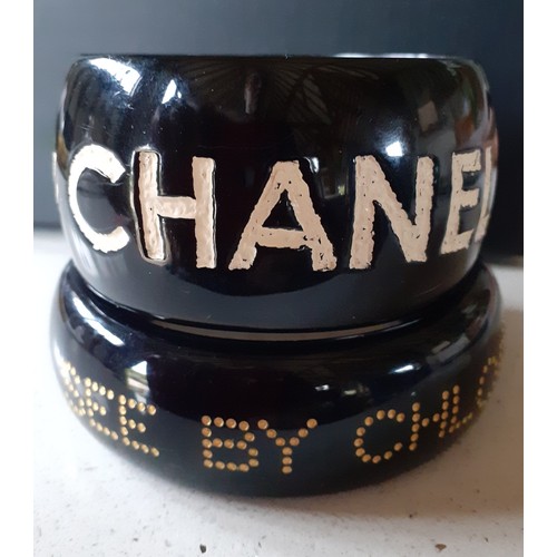 47 - Jessica Kagan Cushman and Chloe-A small 'Ripped Off By Chanel' black bangle with cream inscription, ... 
