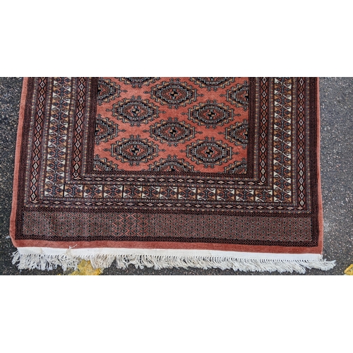 325 - A Bokhara hand woven red ground rug having geometric designs and tasselled ends, 190cm x 126cm
Locat... 