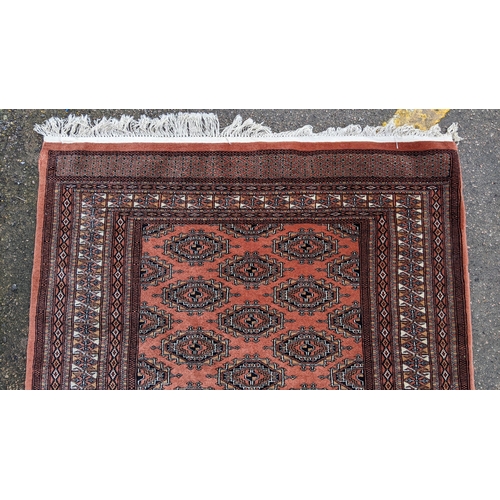 325 - A Bokhara hand woven red ground rug having geometric designs and tasselled ends, 190cm x 126cm
Locat... 