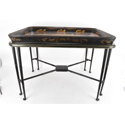 126 - A tray top table having a Victorian black lacquered papier mache tray with a floral border enclosing... 