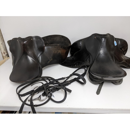 386 - Two leather horse riding saddles, a Prestige 182 saddle, and a Trium 16½ saddle, along with a black ... 