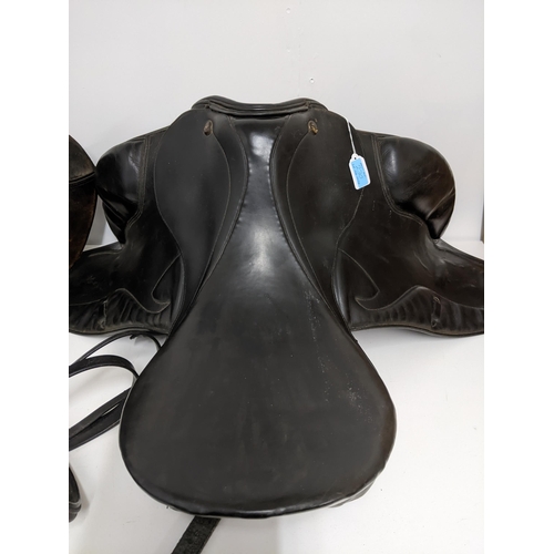 386 - Two leather horse riding saddles, a Prestige 182 saddle, and a Trium 16½ saddle, along with a black ... 