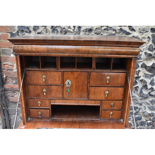 151 - An early 18th century walnut quarter cut secretaire chest on a later stand, having a cavetto moulded... 