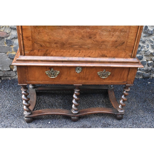 151 - An early 18th century walnut quarter cut secretaire chest on a later stand, having a cavetto moulded... 