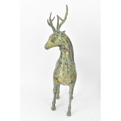 176 - A Chinese patinated bronzed model of a stag, decorated with gilt scroll designs and character marks,... 