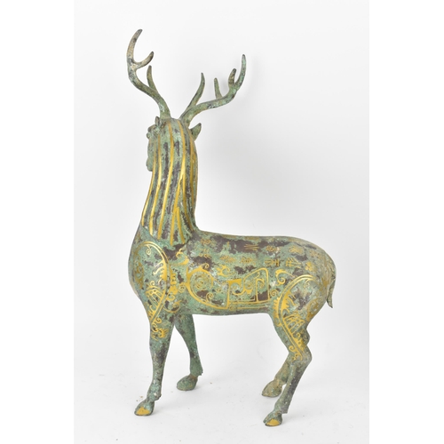 176 - A Chinese patinated bronzed model of a stag, decorated with gilt scroll designs and character marks,... 