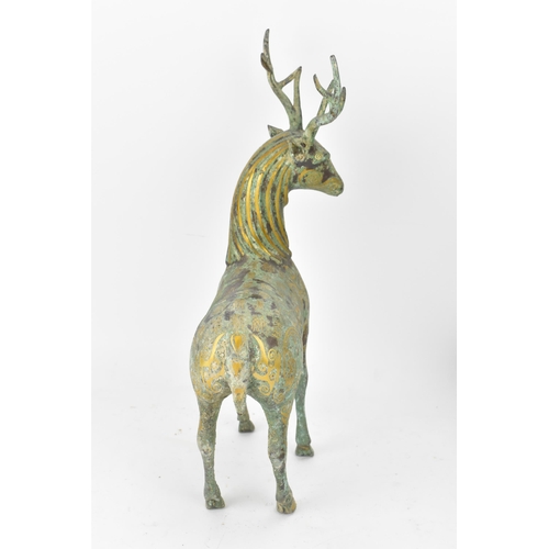 176 - A Chinese patinated bronzed model of a stag, decorated with gilt scroll designs and character marks,... 