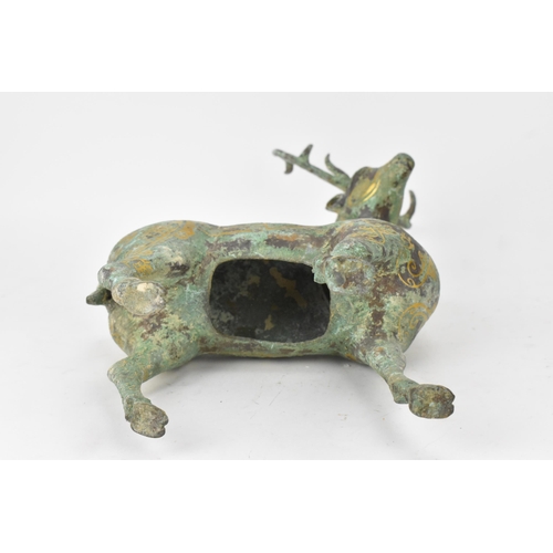 176 - A Chinese patinated bronzed model of a stag, decorated with gilt scroll designs and character marks,... 