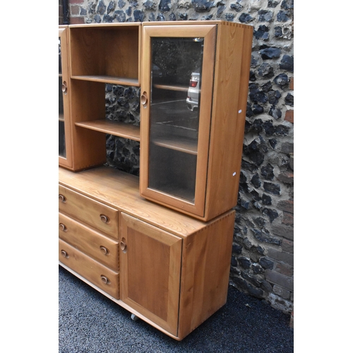 199 - An Ercol Windsor range light elm display cabinet, having three open shelves flanked by two glazed do... 