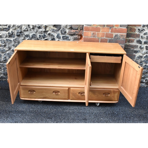 203 - A mid 20th century Ercol Windsor range light elm sideboard, mode 468, having three cupboard doors ab... 