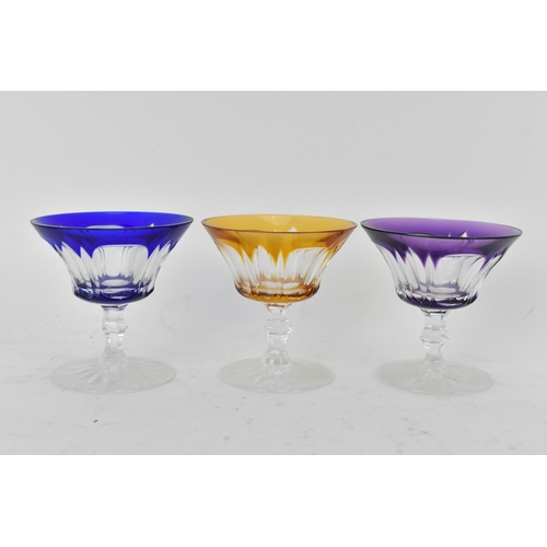 223 - A set of twelve Bohemian coloured coupe glasses having flashed bowls upon faceted and lobed stems an... 