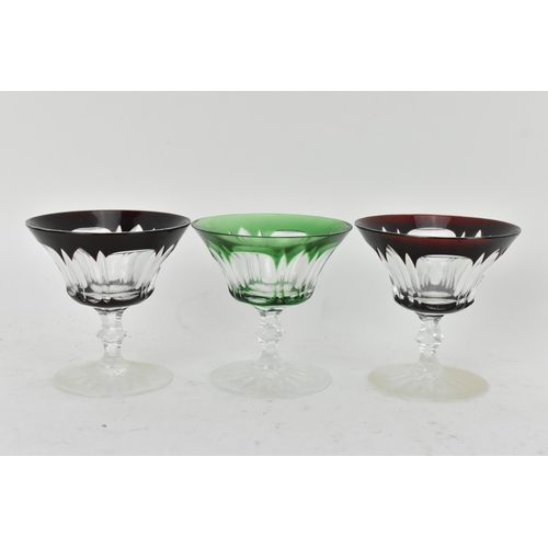 223 - A set of twelve Bohemian coloured coupe glasses having flashed bowls upon faceted and lobed stems an... 