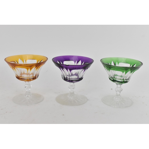 223 - A set of twelve Bohemian coloured coupe glasses having flashed bowls upon faceted and lobed stems an... 