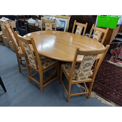 424 - A blonde Ercol oval dining table on a quadruped base with six Ercol dining chairs with upholstered s... 