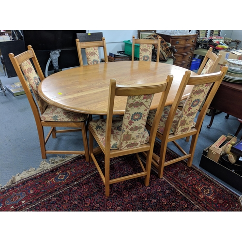 424 - A blonde Ercol oval dining table on a quadruped base with six Ercol dining chairs with upholstered s... 