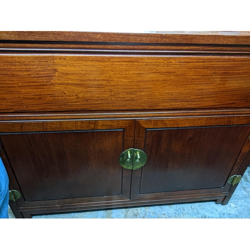 420 - A Chinese rosewood side cabinet with hinged top, twin cupboard doors revealing a fitted partitioned ... 