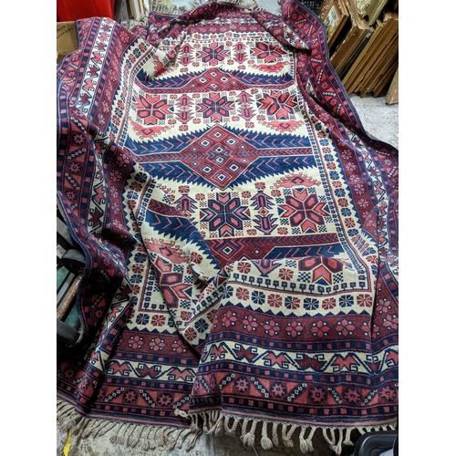 462 - A Turkish Kazakh woollen hand woven carpet in reds, blue and ivory colours, all over geometric and f... 