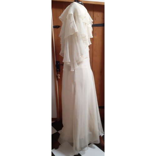 108 - Frank Usher-A 1970's cream chiffon full length evening gown having tiered waterfall sleeves, 32/34