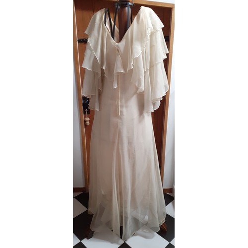 108 - Frank Usher-A 1970's cream chiffon full length evening gown having tiered waterfall sleeves, 32/34