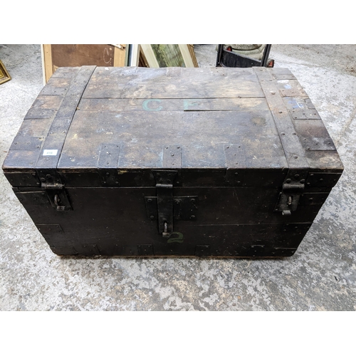 107 - A 19th century wooden travelling chest with iron bound straps and carrying handles 55cm x 94cm x 59c... 