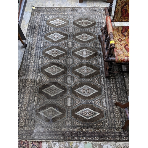 103 - A Middle Eastern handwoven green ground rug having two vertical rows of seven elephant gulls, multig... 