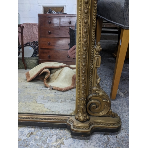 93 - Victorian gilt framed overmantel mirror surmounted with scrolled and stylized leaf decoration enclos... 