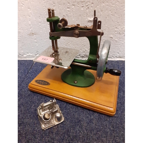 157 - A 1940's Grain child's manual sewing machine together with a silver tone model of a sewing machine, ... 