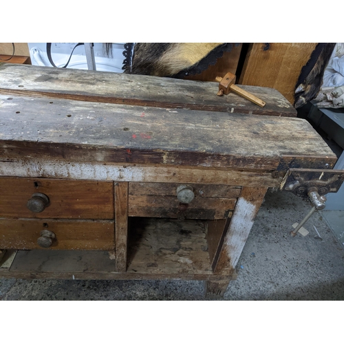 346 - A wooden workbench with an iron vice to the right side, drawers and open storage spaces, on block fe... 