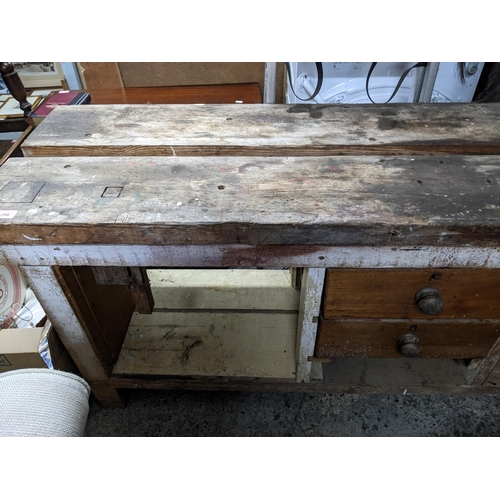 346 - A wooden workbench with an iron vice to the right side, drawers and open storage spaces, on block fe... 