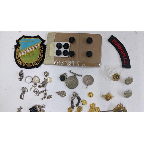 245 - A mixed lot of mainly badges to include a Durham Light Infantry cap badge, and others, together with... 